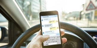 Man hold cellphone while driving. Photo/Shutterstock.