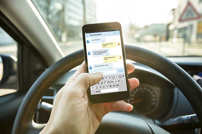 Man hold cellphone while driving. Photo/Shutterstock.