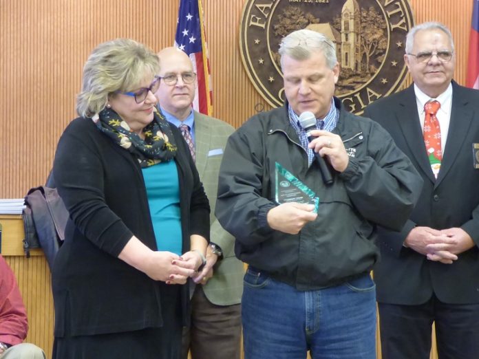 The retirement of longtime Fayette County Finance Department Director Mary Parrott was recently announced. Pictured with Parrot, at left, receiving an award for her service was County Administrator Steve Rapson. In the background were Commissioner Edge Gibbons and Chairman Randy Ognio. Photo/Ben Nelms.