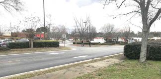 Fayetteville police are shown behind a police tape in a restaurant parking lot off Hwy. 85 jto the north of the shooting incident Monday. Photo/Ben Nelms.