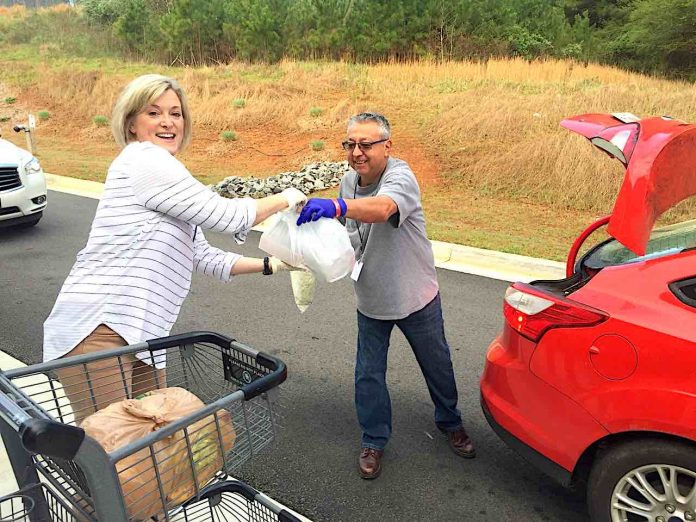 Real Life Centers volunteers Vicki Free and George Holguin assist with serving families with food at the Real Life Center, 975 Hwy 74 North, Tyrone on Thursday, March 19. Photo/Real Life Center.