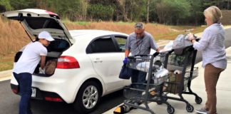 Real Life Center volunteers Vicki Free, George Holguin, and Jennifer Dobbs serve drive-thru clients.