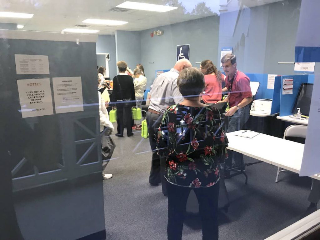 Through the looking glass, workers at the Fayette County Elections Office receive ballots from precincts. Photo/Ben Nelms.