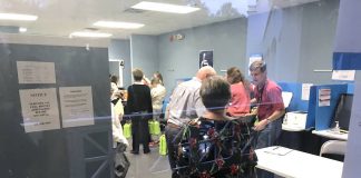 Through the looking glass, workers at the Fayette County Elections Office receive ballots from precincts. Photo/Ben Nelms.