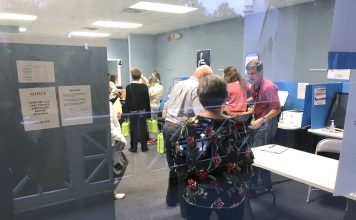 Through the looking glass, workers at the Fayette County Elections Office receive ballots from precincts. Photo/Ben Nelms.