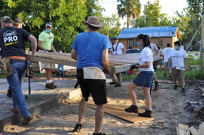 The group joins together to raise the newly framed walls: (L-R) David Venables (with Lowe’s corporate office), Doug Higgins, Charlie Ginn, Denton Erickson, Faye Livingston.  They are moving the first exterior wall into place. Photo/Square Foot Ministry.