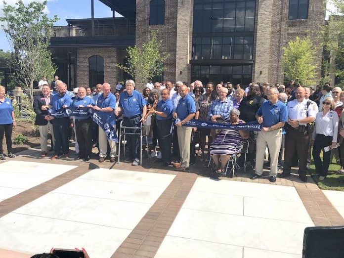 The Fayetteville City Council and City Manager Ray Gibson, all in blue shirts, cut the ribbon July 14 signifying the grand opening of the new Fayetteville City Hall on West Stonewall Avenue. They were joined for the event by a large group of Fayetteville staff and citizens, and elected officials from throughout Fayette County. Photo/Ben Nelms.