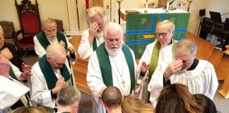 Bishop David Epps (center) and church members in prayer. Photo/submitted.