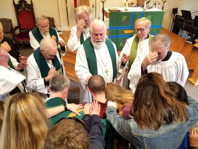 Bishop David Epps (center) and church members in prayer. Photo/submitted.