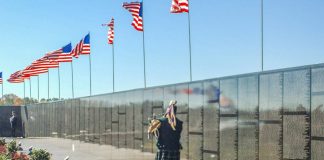 A Vietnam veteran plays the bagpipes at the Dignity Memorial Vietnam Wall. The exhibit crisscrosses the country each year, allowing millions of visitors to see and touch the black, mirror-like surface inscribed with the names of more than 58,000 Americans who died or are missing in Vietnam. The wall honors all U.S. veterans and is dedicated to Vietnam veterans. Photo/U.S. Navy .