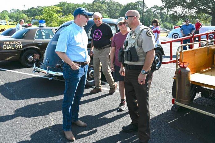 Pastor Josh Saefkow (L, with blue baseball cap) talks with Fayette County Sheriff Barry Babb during the church's car and craft show in June 2023 at the church on Flat Creek Trail. Photo/Roger Alford.